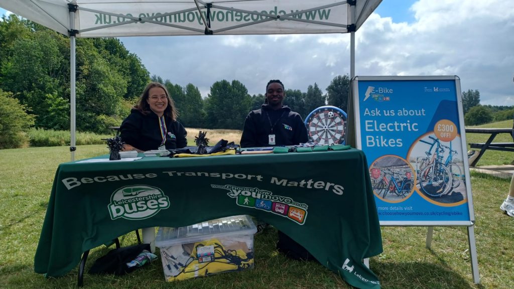 Two Choose How You Move officers sit at a table under a gazebo at a park to promote the Dino T-Reks trails.