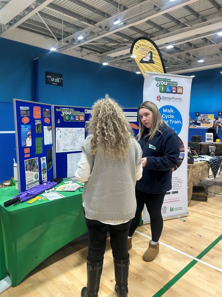 A Choose How You Move officer talking to a person at a Choose How You Move community roadshow stall in Coalville