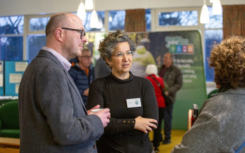 A man and a woman talking amongst stalls at the Cycling, Walking and Wheeling Forum