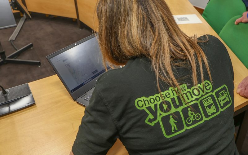 A person wearing a black Choose How You Move-branded top typing on a laptop