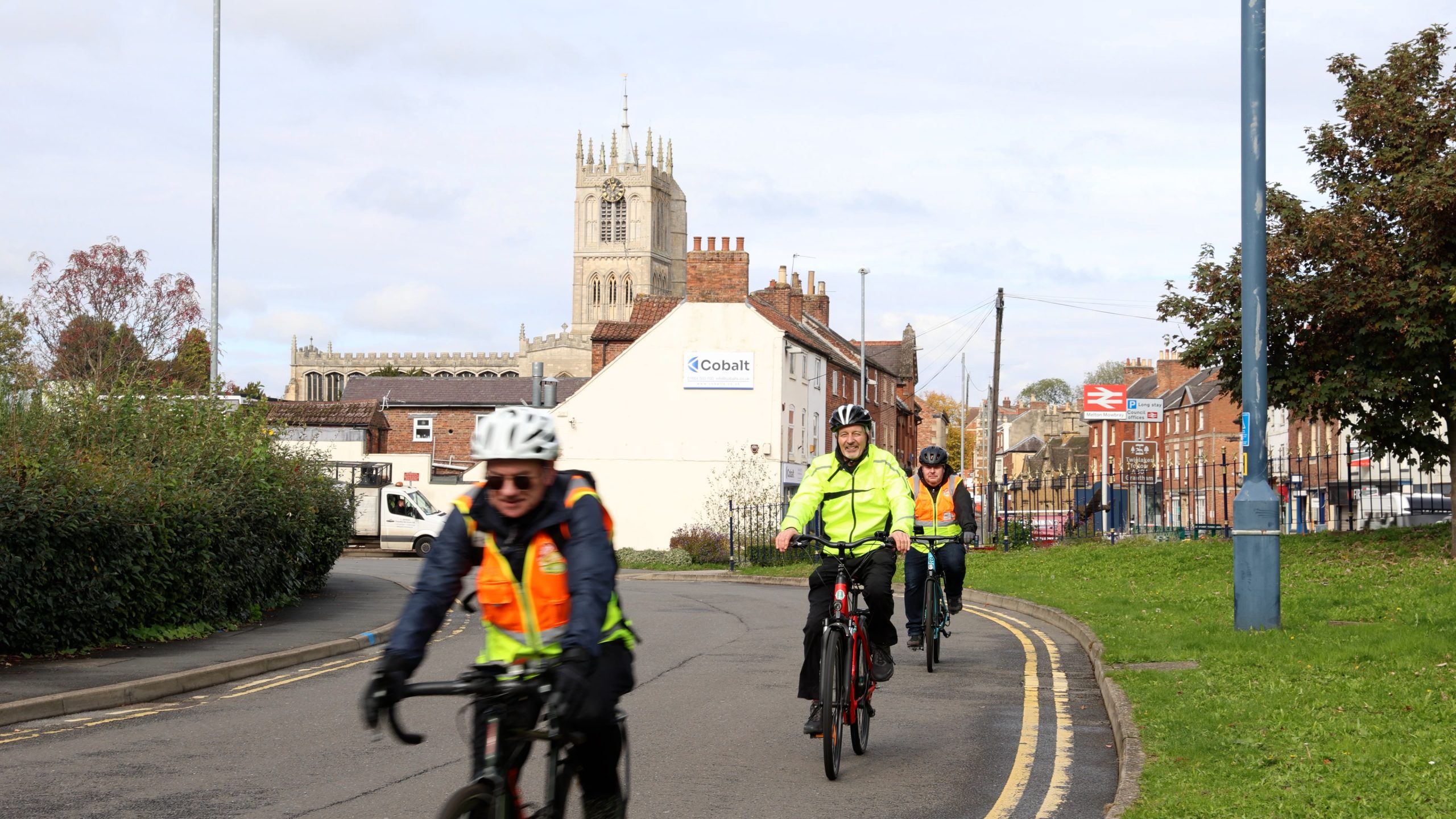 Three people in hi-vis jackets biking down a road in Leicestershire