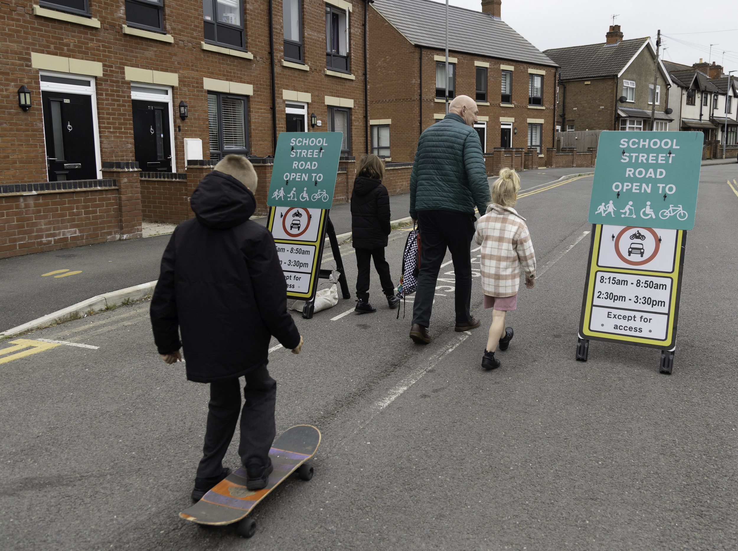 people walking between signs for a School Street as part of the Leicestershire School Streets programme