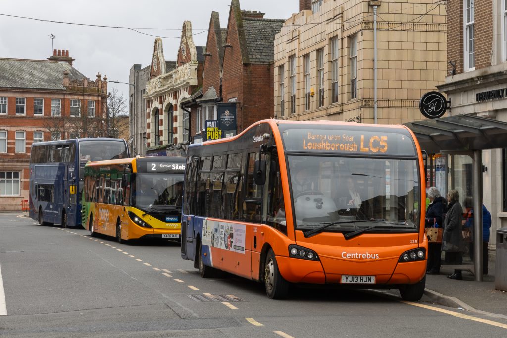 A row of buses lined up at bus stops on a road in Leicestershire. For buses, Leicestershire businesses, new developments, public transport.