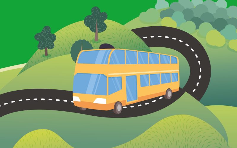 A yellow bus travelling along a road as part of the Summer by Bus campaign