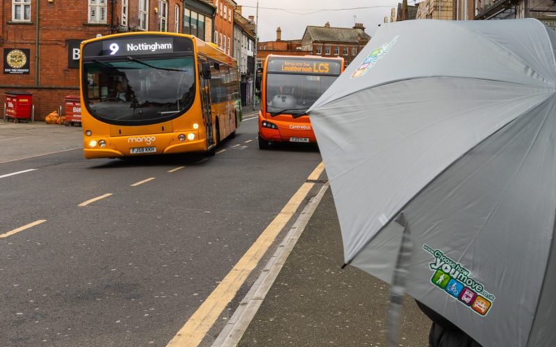Person waiting for a bus with an umbrella. For public transport, Leicestershire businesses, business programme, new developments.