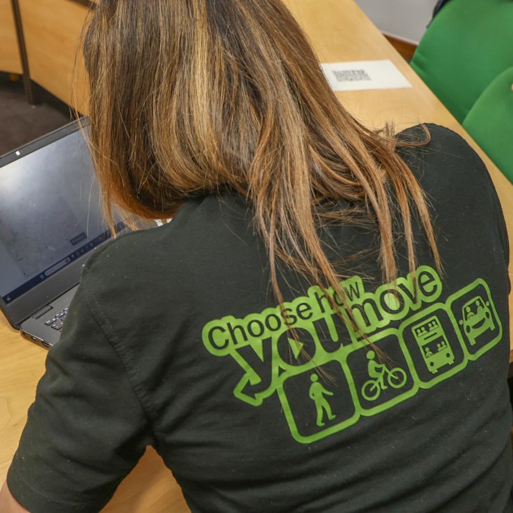 A person wearing a black Choose How You Move-branded top typing on a laptop