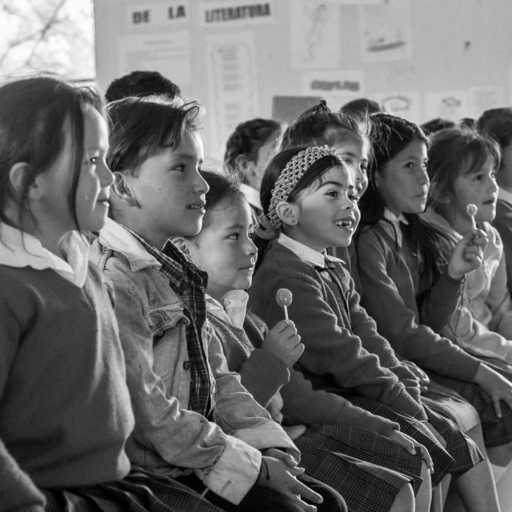A line of young schoolchildren in uniform listening during an assembly. Some of the children are holding lollipops - for schools Active Travel Calendar