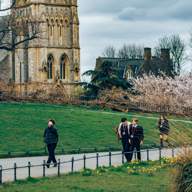 Schoolchilren walking on a path against a backdrop with an old church in a park - for schools Active Travel Calendar