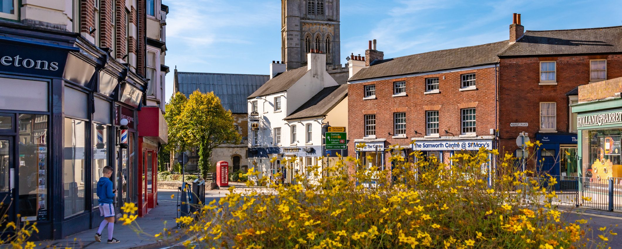 A view of St Mary's Church from town centre in Melton Mowbray. A young man walks on the pavement in the distance.