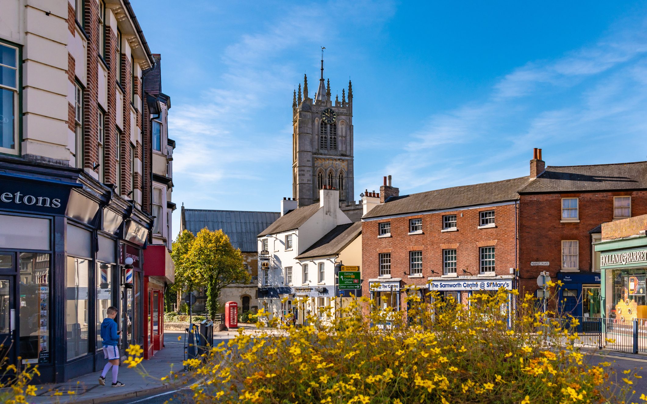 A view of St Mary's Church from town centre in Melton Mowbray. A young man walks on the pavement in the distance.