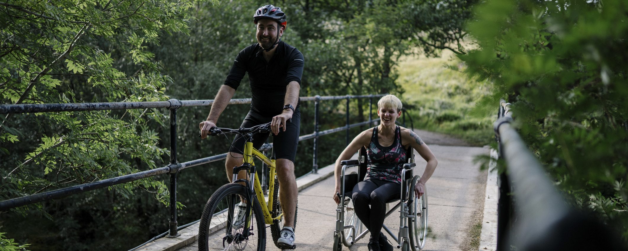 Couple exercising together on a bicycle and in a wheelchair.