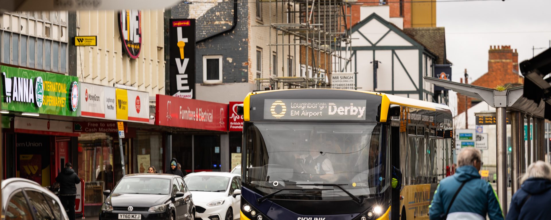 A yellow bus heading to Derby driving down a road in Loughborough, Leicestershire.