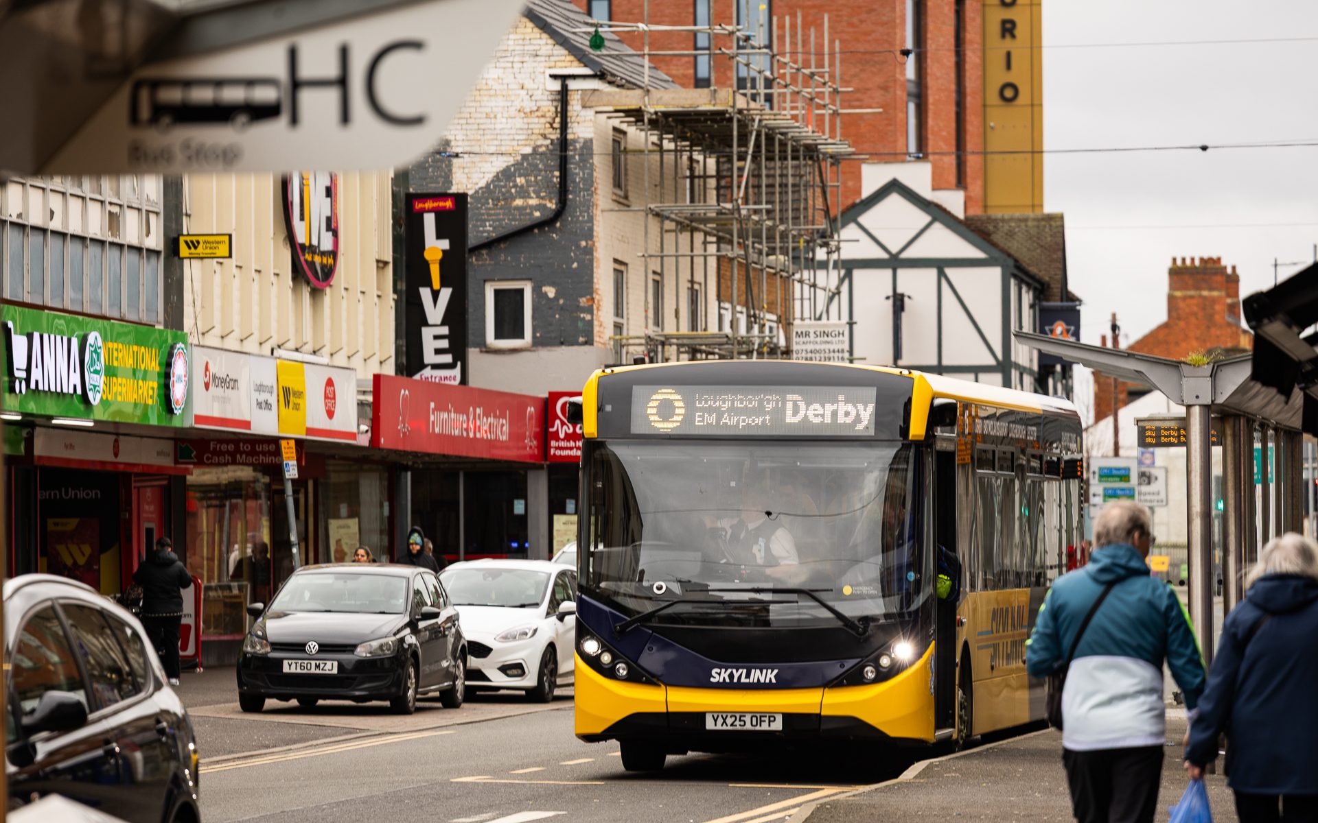 A yellow bus heading to Derby driving down a road in Loughborough, Leicestershire.