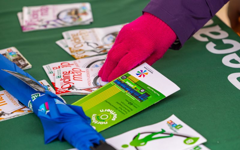 a person with red gloves picking up a leaflet from Choose How You Move - for communities roadshow