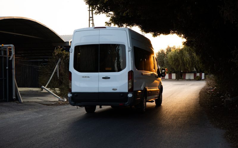 A white minibus van driving on a road into the sunset. For accessible transport, community transport driving.