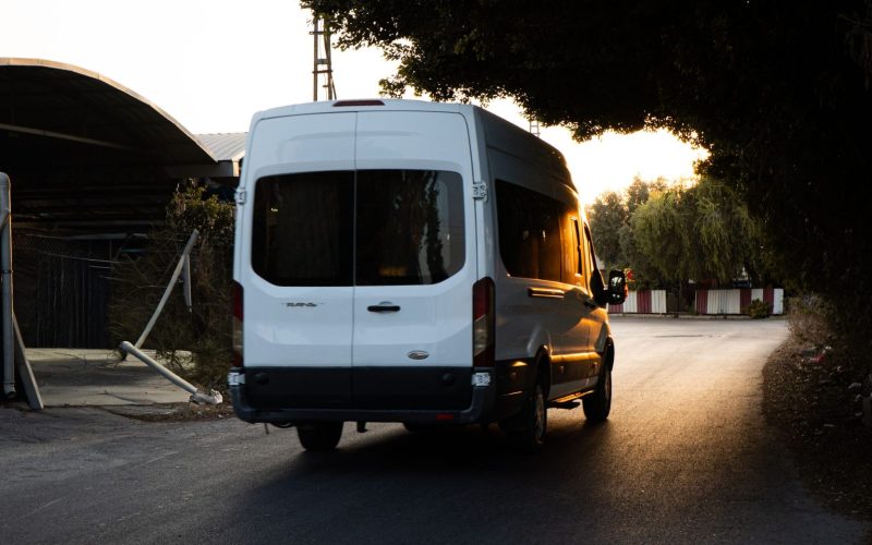 A white minibus van driving on a road into the sunset. For accessible transport, community transport driving.