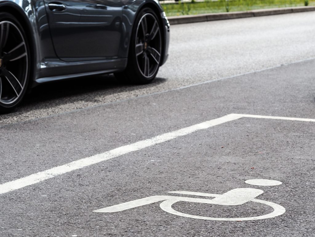A car parked on the opposite side of the road to a disabled parking space, painted onto the road in white paint. For accessible transport and blue badge passes.