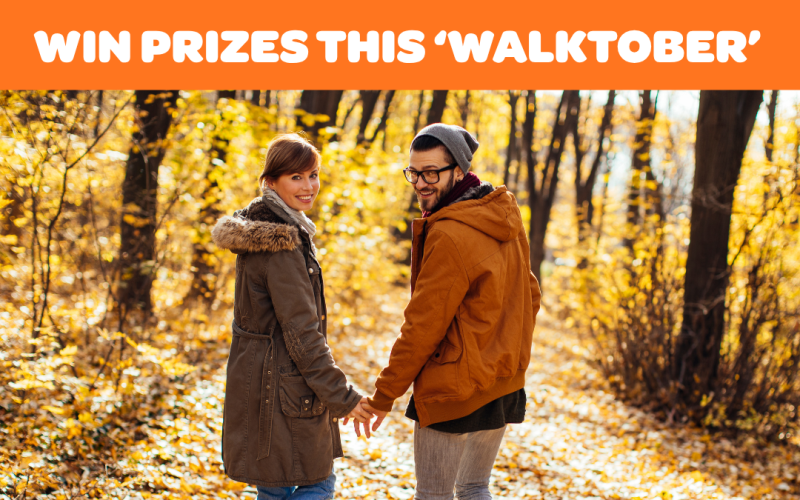 Two people walking down a woodland path with leaves on the floor. For BetterPoints promotion during Active Travel Month