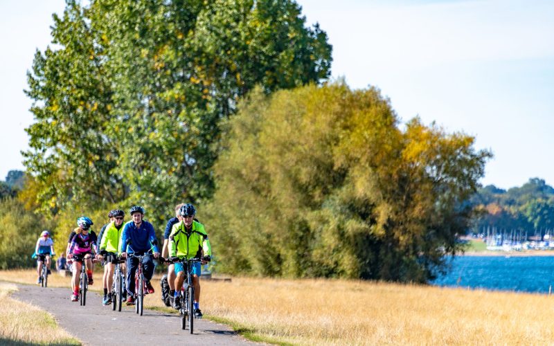 A group of adults cycling on paths on Rutland Water, Leicestershire on a sunny day.