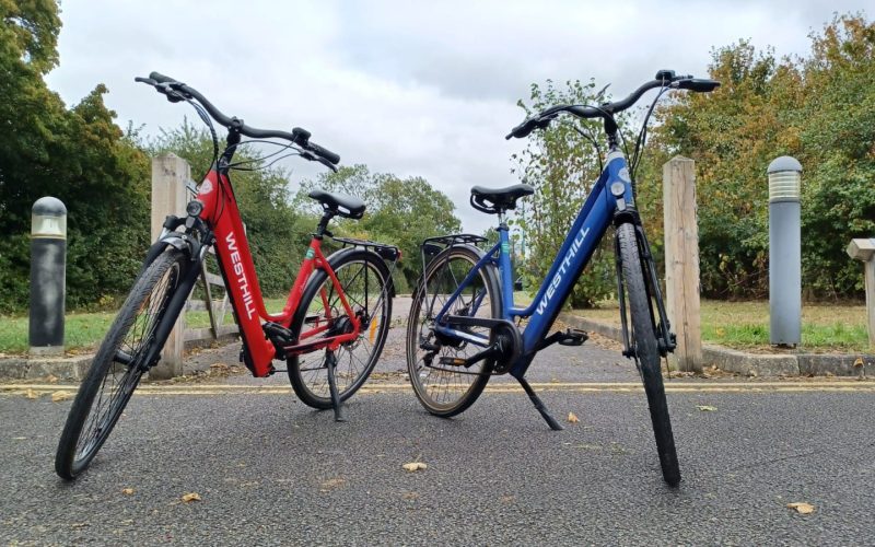 two e-bikes, one red and one blue, parked and turned towards the viewer.