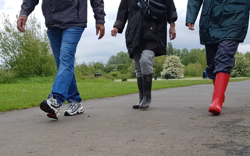 three people in coats and wellies walking on a path