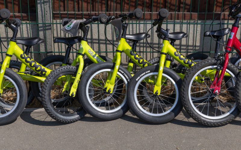 Children's bikes lined up against school gate railings.