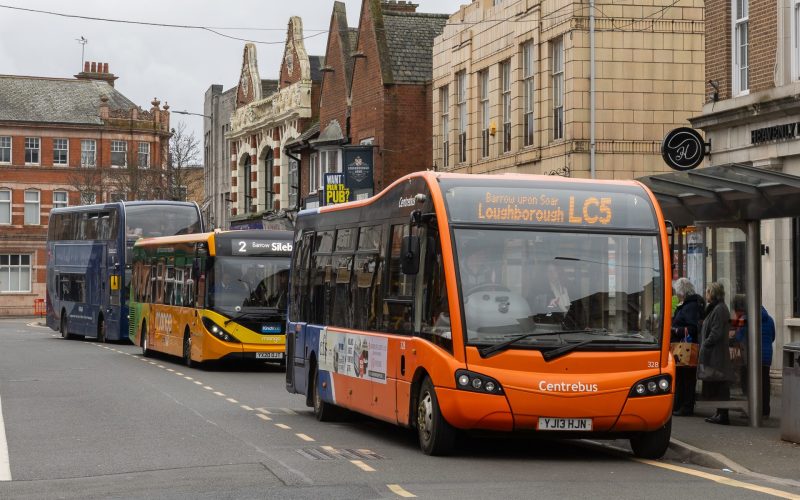 A row of buses lined up at bus stops on a road in Leicestershire. For buses, Leicestershire businesses, new developments, public transport.